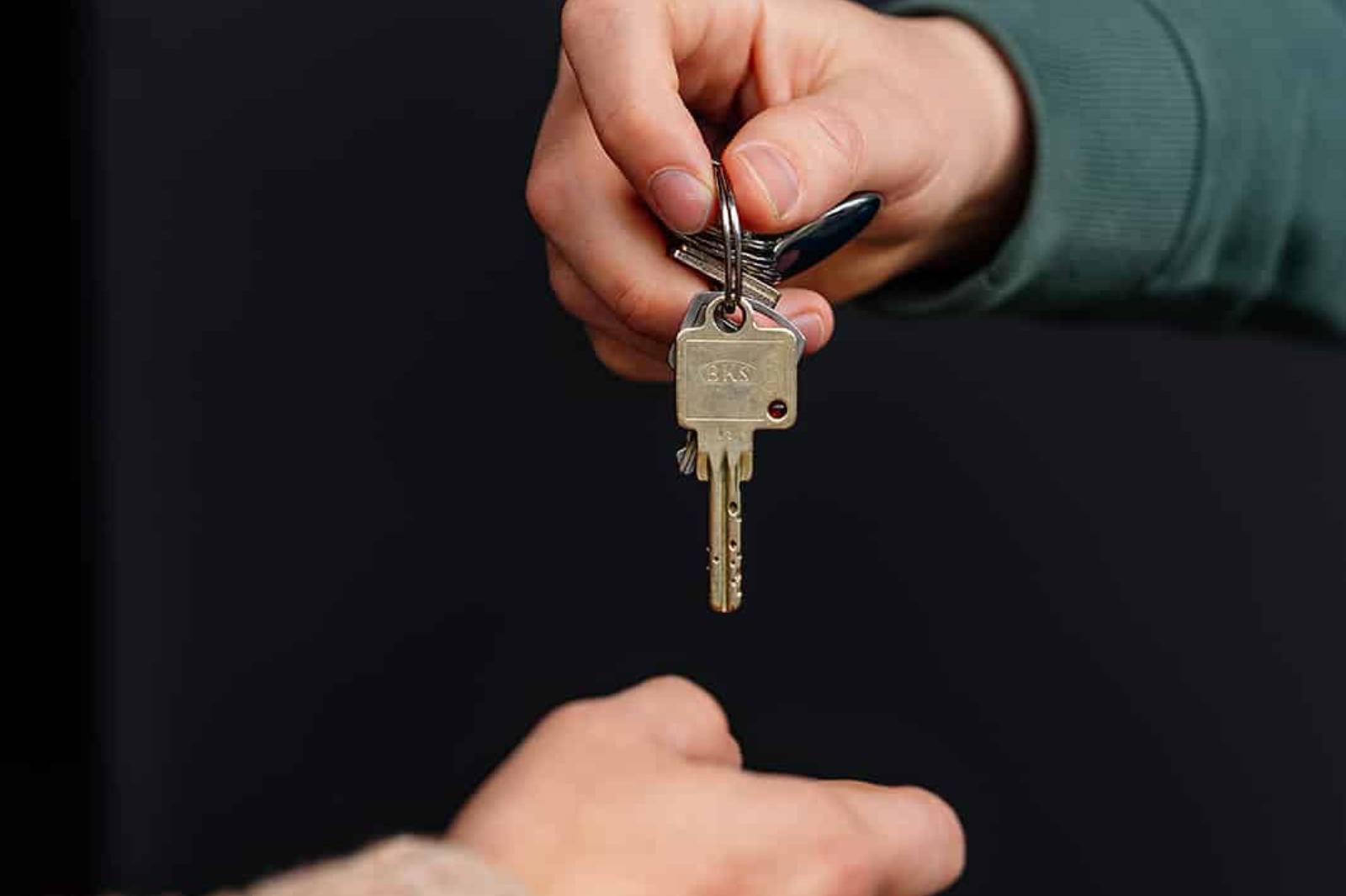 Overdracht van een sleutelbos tussen twee personen als illustratie van vastgoedbeheer