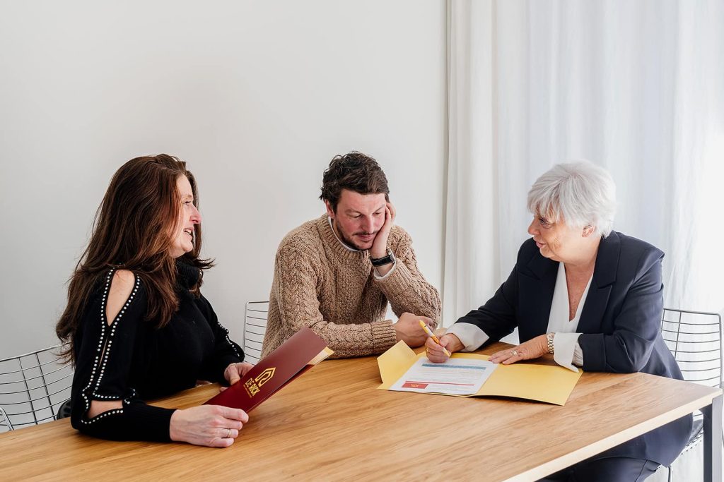 Kopers bespreken aankoopkosten en registratierechten met een vastgoedmakelaar voor een woning in 2026