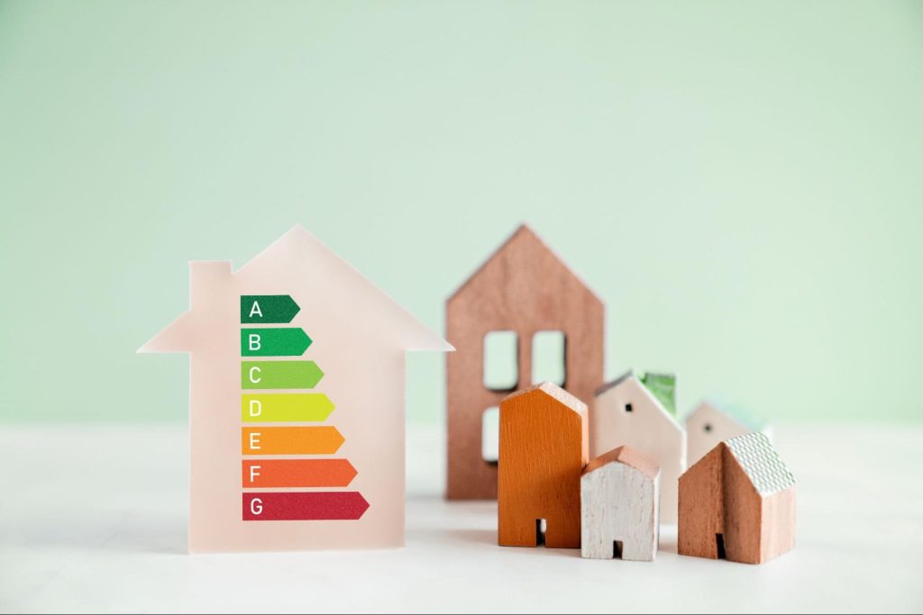 Houten huisjes naast een woning icoon met energieklasse labels A tot G die de epc-score van een woning voorstellen